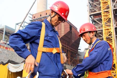 進入高空作業前，同事正在幫他穿戴高空安全帶